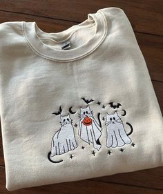 Spooky cats embroidered crew neck sweatshirt. Available in different colors.  Gildan crew neck 50/50 cotton/poly blend. Super cozy, classic fit. Buy 2 sizes up for the oversized fit. Please refer to size and color chart when ordering.  Please note that items are made to order and we don't do cancellations or returns unless the item is damaged. Check out our other great listings and feel free to contact us for personalization. Crew Neck Sweater With Cat Design For Fall, Fall Cotton Sweater With Cat Print, White Cat Design Sweatshirt For Fall, Fall Crew Neck Sweater With Cat Design, Halloween Embroidered Crewneck, Cotton Crew Neck Sweater With Cat Design, Fall Crew Neck Sweatshirt With Cat Design, Spooky Crewneck, Black Crew Neck Halloween Sweatshirt