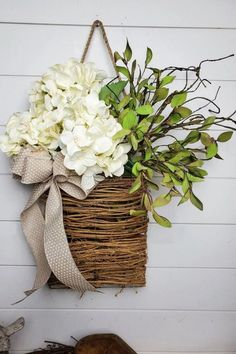 a basket filled with white flowers hanging on a wall next to a pair of shoes