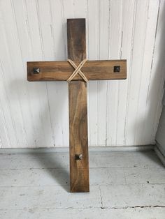 a wooden cross sitting on top of a white floor in front of a wall with wood planks