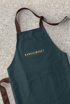 a dark green apron with the words bankhrornet printed in gold on it