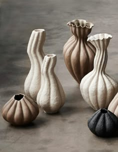 five vases sitting on top of a cement floor next to each other in different shapes and sizes