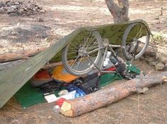 there is a bicycle parked next to a tent in the woods with it's roof up