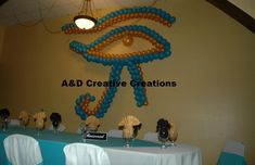 the table is set up for an event with blue and brown balloons hanging from the ceiling