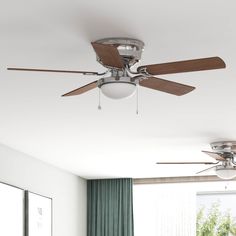 a ceiling fan in a room with green curtains