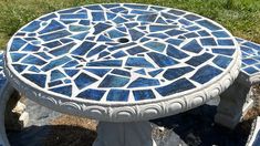 a blue and white mosaic table sitting in the grass