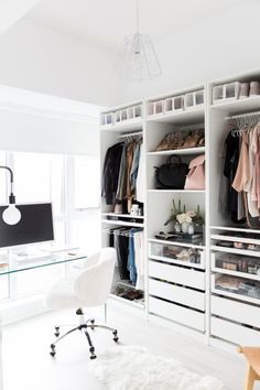 a white closet filled with lots of clothes and bags next to a computer monitor on top of a desk