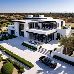 an aerial view of a modern house with cars parked in the driveway and landscaping around it