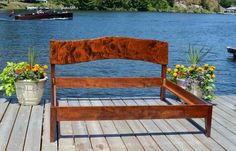 a wooden bench sitting on top of a wooden pier next to water with boats in the background