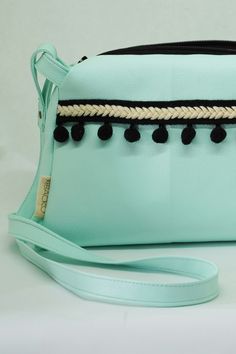 a mint green purse with black tassels on the front and white trimming