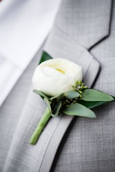 a boutonniere with a white flower on the lapel of a suit