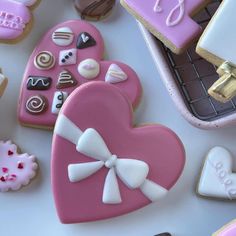 several decorated cookies in the shape of heart and bow on top of a white table