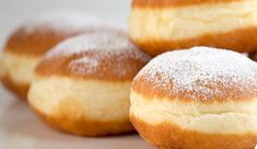 four sugar filled doughnuts sitting on top of a white countertop next to each other