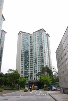 two tall buildings sitting next to each other on a city street in front of trees