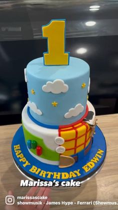 a blue and yellow birthday cake with the number one on it's top tier