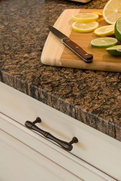 a cutting board with sliced lemons and limes on it next to a knife