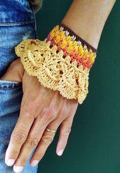 a close up of a person's hand wearing a crocheted wristband