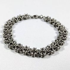 A chainmaille bracelet using the "Celtic Visions" weave. I use tiny pliers to open each individual ring, weave it into the chain and then close it, carefully lining up the ends so they're flush. * Won't tarnish or change color over time * Can be cleaned with warm soapy water * Made with 20 gauge stainless steel jump rings and a 9mm stainless steel clasp * Bracelet length includes the length of the clasp. If you don't know your bracelet size, measure around your wrist and then add 1/4" to 1", depending on how tight you'd like your bracelet to fit. A flexible measuring tape is a great way to measure if you have one - if not, you can use string or a strip of paper to measure your wrist and then hold it up to ruler to find the length. Metal Bracelets With Jump Ring For Jewelry Making, Stainless Steel Chain Link Jewelry With Jump Ring, Adjustable Stainless Steel Bracelet With Jump Ring, Stainless Steel Chainmail Bracelet As Gift, Metal Box Chain Bracelet, Nickel-free Metal Braided Bracelets, Hypoallergenic Metal Chain Link Bracelet, Hypoallergenic Metal Bracelets For Jewelry Making, Chainmail Metal Bracelet