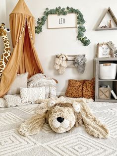 a stuffed animal laying on top of a bed next to a wall mounted giraffe