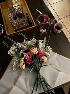 a bouquet of flowers sitting on top of a table next to a wine glass and other items