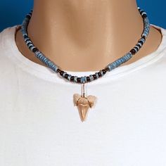 This is a 17.75-inch-long necklace. Strung with 4-5mm Round Denim Blue Dyed Puka Shell Beads, Black Glass Beads, and 4-5mm Coconut Beads. Attached are genuine fossil shark teeth from the deserts of Morocco. These teeth measure a minimum of 1 inch (25.3mm) long, see Pic to see how shark teeth are measured. We harden these teeth for durability while being worn and wire them with silver plated copper wire. The age of these Fossil Sharks teeth is between 50 and 70 million years old. We have 3 of these necklaces to choose from. In stock. Shipped daily from Florida USA. Sharks Teeth, Shark Tooth Necklace, Tooth Necklace, Blue Dye, Puka Shell, Shark Tooth, Shark Teeth, Florida Usa, Shell Beads