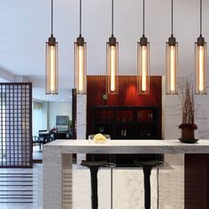 a modern kitchen with marble counter tops and hanging lights above the island in front of it