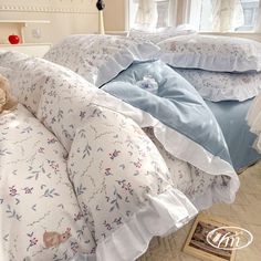 a teddy bear sitting on top of a bed next to pillows and sheets with ruffles