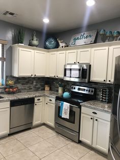 a kitchen with white cabinets and stainless steel appliances, including an oven, dishwasher, microwave, and refrigerator