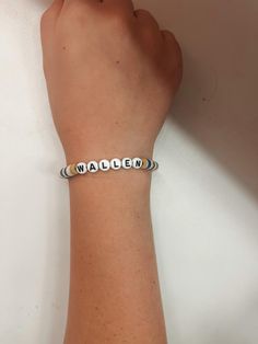 a woman's hand holding onto a bracelet with the word maden written on it