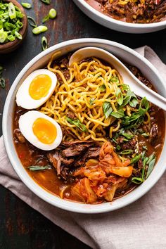 two bowls filled with noodles, meat and eggs