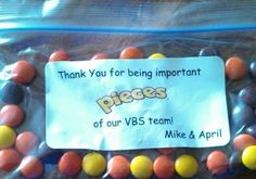 a bag filled with lots of candies on top of a wooden table next to a sign that says, thank you for being important pieces of our vbs team