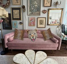 a living room with pink couches and pictures on the wall behind it, including a leopard head