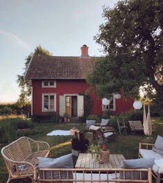 a wooden table sitting in the middle of a yard next to a red house with white balloons