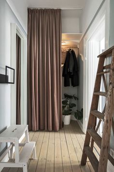 a room with a ladder, coat rack and clothes hanging on the wall next to it