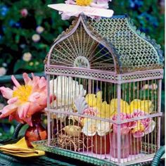 a birdcage filled with flowers sitting on top of a green table next to a banana