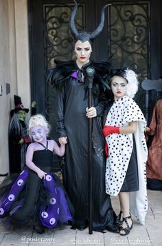 three people dressed up as maleficents and one is holding a microphone in front of a building