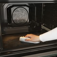 a person cleaning the inside of an oven with a cloth on it's side