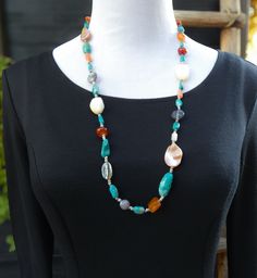 As an art lover, you'll appreciate this handcrafted treasure necklace by a Santo Domingo Native American artisan. The earthy, multi-stone design, adorned with stunning beads and seashells, is a one-of-a-kind piece that will become your signature piece. Its vibrant semi-precious stones and shiny shells make it a true statement. Length: 28 1/2" cannot be extended Weight: 59 grams Vintage never worn Bohemian Shell Necklace With Gemstone Beads, Bohemian Beaded Agate Long Necklace, Bohemian Agate Beaded Long Necklace, Bohemian Long Agate Beaded Necklace, Turquoise Agate Necklace With Colorful Beads, Artisan Beaded Necklace With Gemstone Beads For Beach, Bohemian Long Necklace With Natural Stones For Beach, Bohemian Gemstone Necklace For Beach, Bohemian Turquoise Shell Necklace With Natural Stones