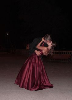 a man and woman are kissing in the street at night with their arms around each other