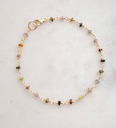 Spread creativity and joy with this multicolor gemstone Tourmaline bracelet! This handmade beauty features natural Tourmaline crystals in a variety of hues, including pink, black, green, and yellow. Each bracelet is unique, with no set pattern, making each one a one-of-a-kind. It comes in your choice of sterling silver or 14k gold filled. Tourmaline Meaning: The birthstone for October, Tourmaline is believed to promote inspiration, boost confidence, and combat fear. Stone Size: Average 3-4mm Mat Gold Bracelets With Natural Stones And Tourmaline, Gold Tourmaline Bracelets With Natural Stones, Elegant Multicolor Tourmaline Beaded Bracelets, Dainty Multicolor Gemstone Bracelet, Dainty Multicolor Gemstone Beads Bracelets, Spiritual Multicolor Tourmaline Beaded Bracelets, Tourmaline Meaning, Tourmaline Bracelet, Set Patterns