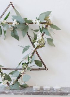 branches with white flowers and green leaves on them are arranged in the shape of an x