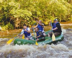 a group of men riding on the back of a green raft