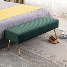 a green bench sitting on top of a gray rug next to a bed with yellow sheets