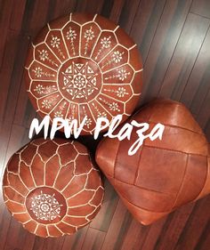 three brown leather poufles sitting on top of a wooden floor