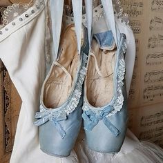 two pairs of blue ballet shoes sitting on top of a bed