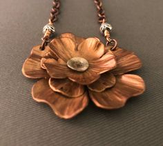 "Three layers of copper that were cut, hand hammered for texture then cold connected and topped with a silver center. The flower is 1.75\" across. The piece is suspended from a copper link chain that is joined to the pendant with a hand wired metal bead. The chain including the bead is 20\". The chain has a copper lobster claw closure. The flower was oxidized to bring out all of the hand texturing on the petals. The flower was also given an acrylic coating to finish it. NC1289" Copper Clay, Purple Flower Necklace, Purple Pendant Necklace, Copper Work, Peacock Jewelry, Copper Jewellery, Blue Peacock, Copper Pendant, Long Pendant Necklace