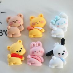 a group of small plastic toys sitting on top of a white table next to a clock