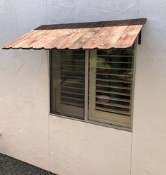 a cat sitting on the ledge of a window sill in front of a building