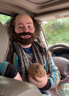 a man with long hair and beard holding a stuffed animal in his hand while sitting in the back seat of a car