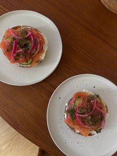 two white plates topped with food on top of a wooden table next to each other