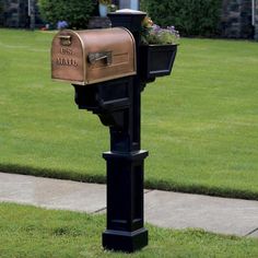 a mailbox with flowers in it on the side of a sidewalk next to grass